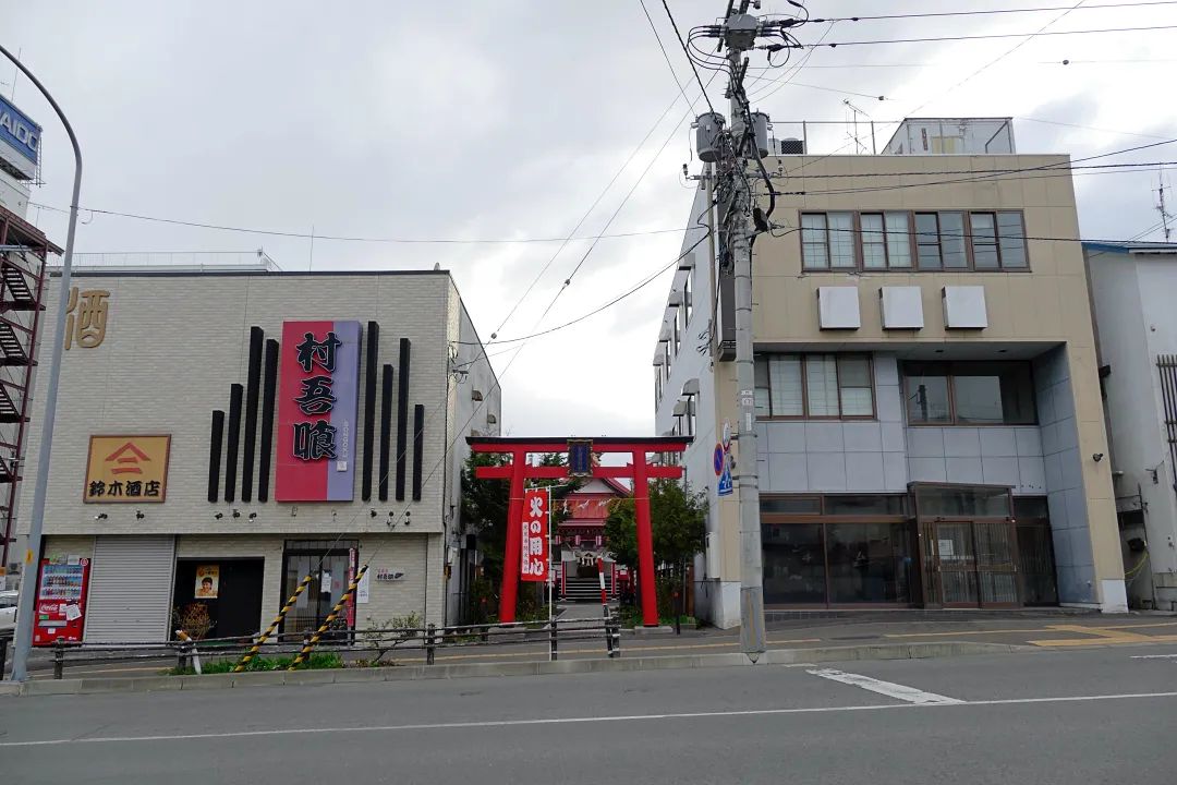 建物の間に建つ北見稲荷神社の鳥居